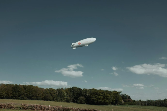 a large white balloon flying over a lush green field